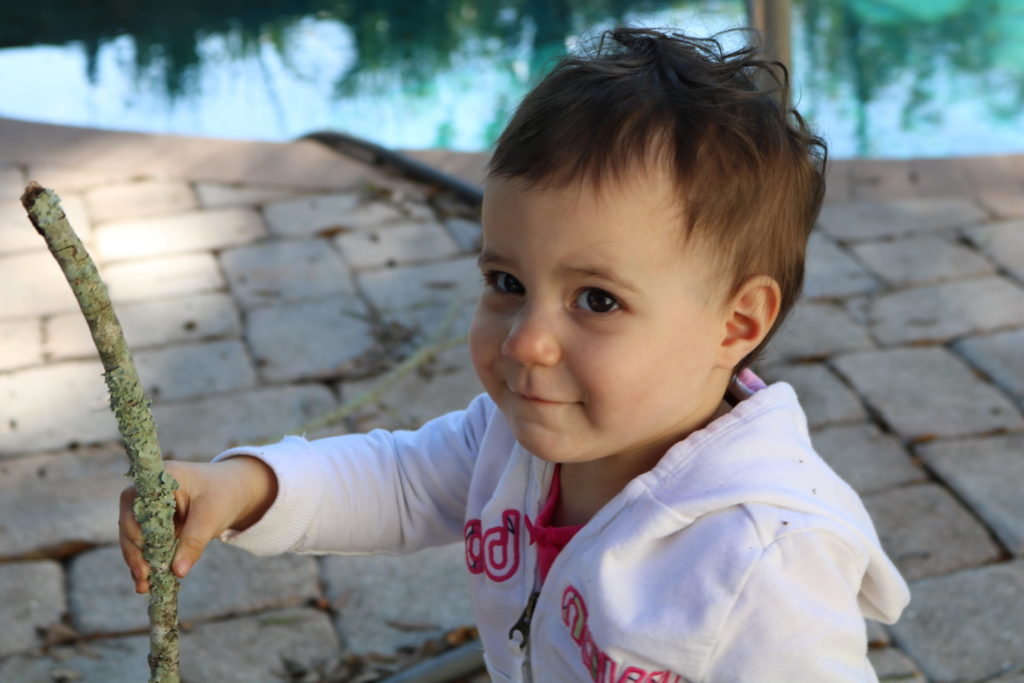 A toddler holding a stick and smiling