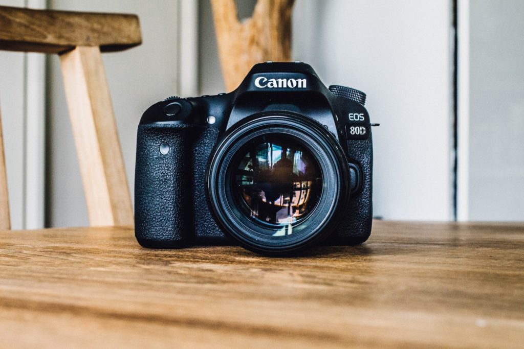A black Canon digital camera sitting on a wooden tabletop