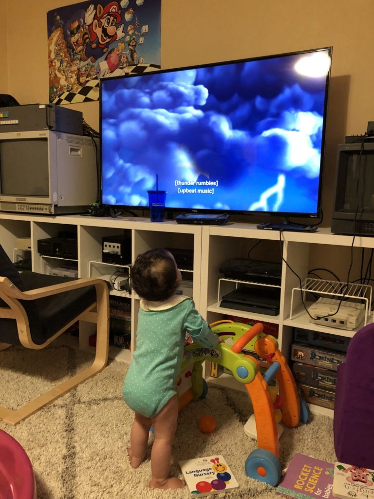 A baby watching TV while wearing arm restraints after palate repair surgery